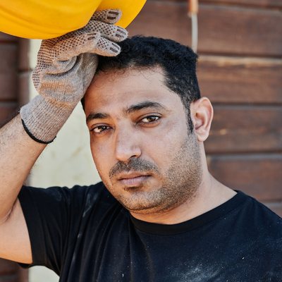 Tired construction worker holding his hard hat