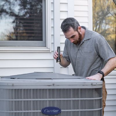 Technician inspecting an outdoor HVAC unit