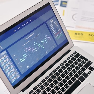 Laptop displaying account data next to printed documents
